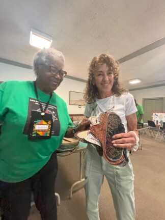 Two people with The Pan African Sisterhood Health Initiative Holding a pad.