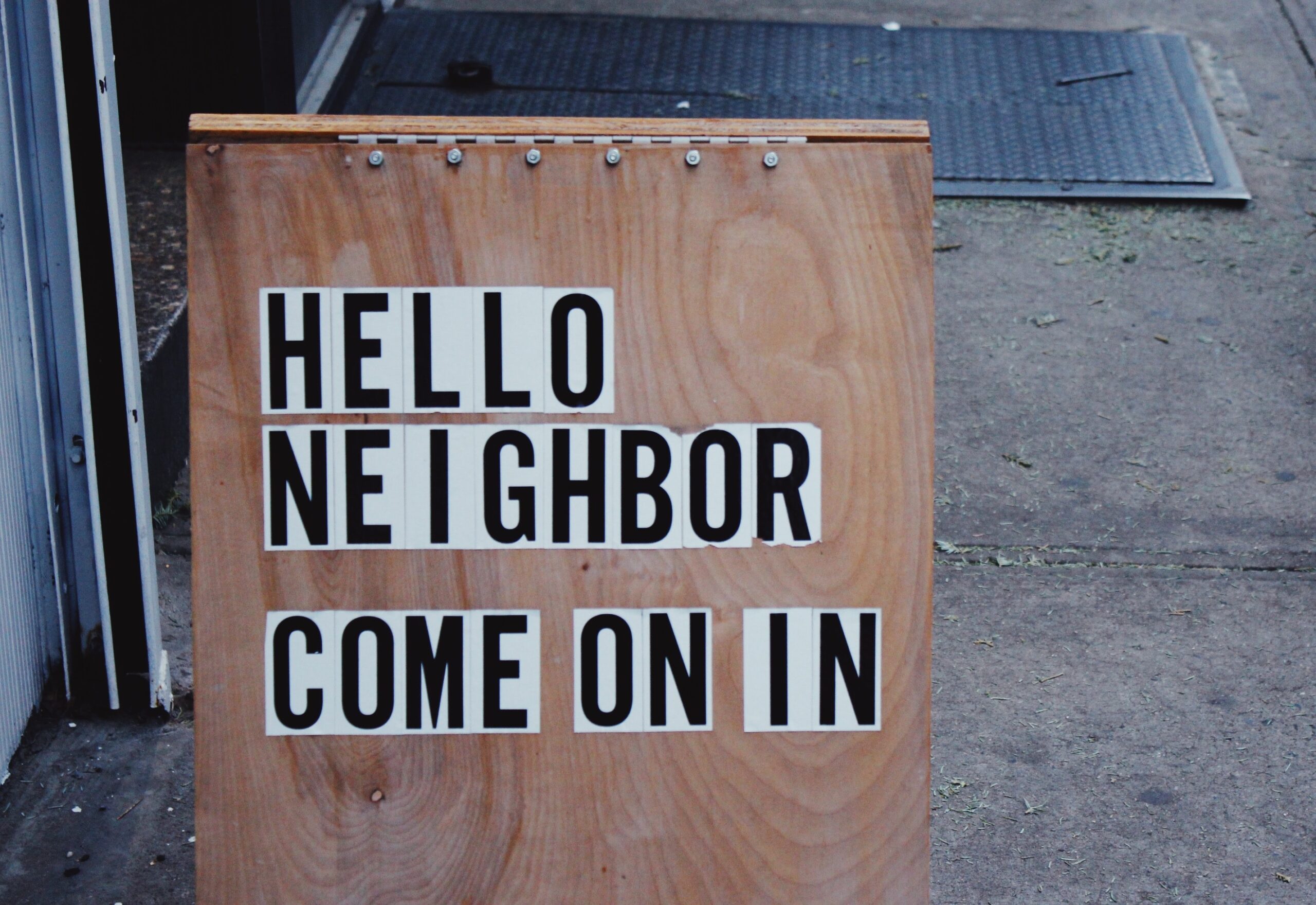 Board that says "Hello Neighbor Come on In"