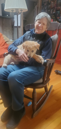 Demie Kurtz in rocking chair holding Golden Retriever puppy