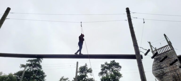 Deputy General Secretary, Christie Duncan-Tesmmer navigating a high ropes course tethered to a safety harness on a cloudy day